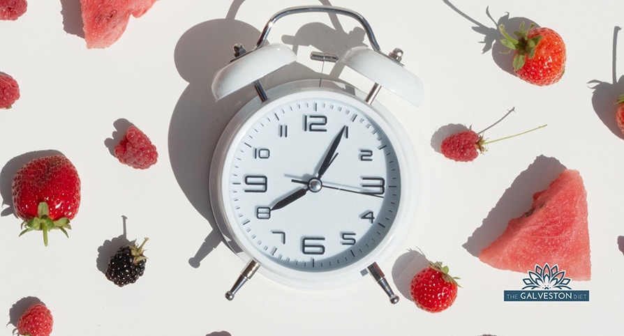 Intermittent fasting clock surrounded by fruit