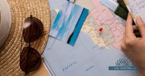 Featured image for the Healthy Travel tips blog post of a map with a printed photo on top as well as a sun hat and some sunglasses.