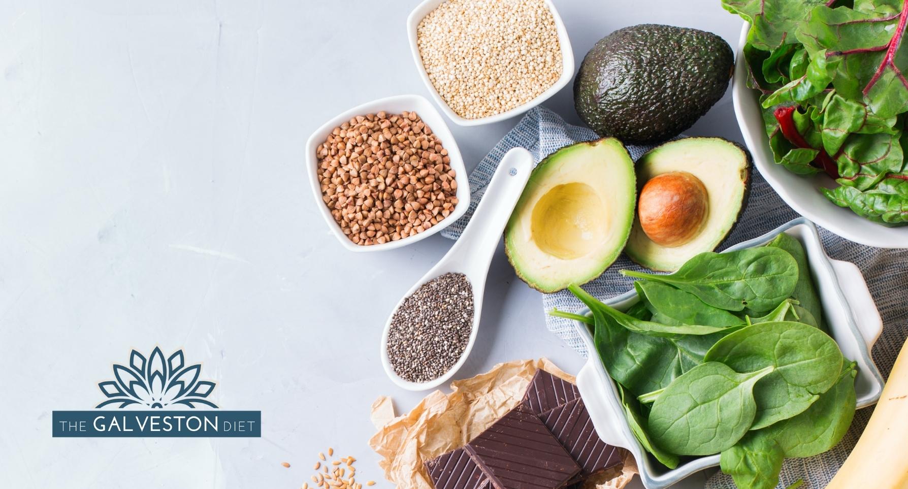 Blog post featured image with avocados, spinach, nuts and seeds. All foods rich in magnesium for menopause symptoms.